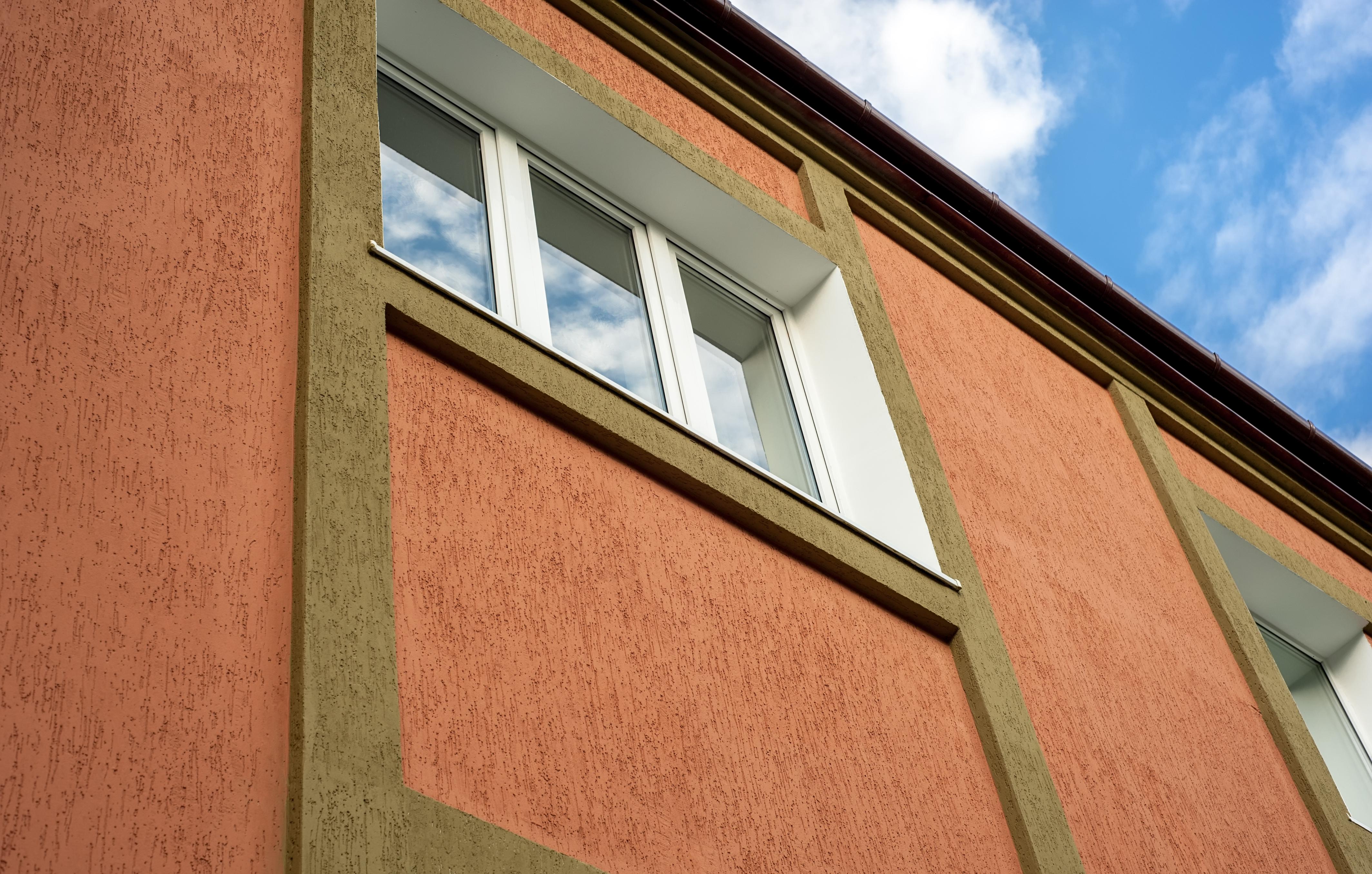 architectural details. window in a building with a brown stucco.